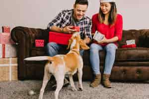 Foto gratuita pareja sonriente con perro en navidad