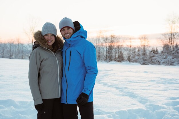 Pareja sonriente de pie sobre un paisaje nevado