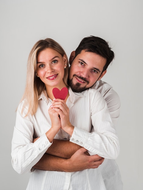 Pareja sonriente posando con corazón para el día de San Valentín