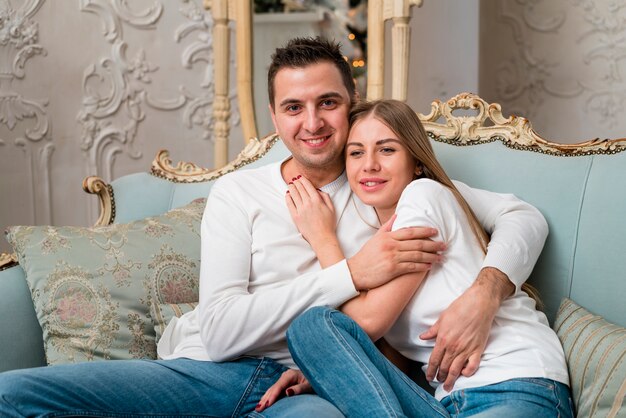 Pareja sonriente posando felizmente en el sofá