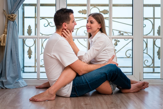 Pareja sonriente posando de lado mientras está abrazada