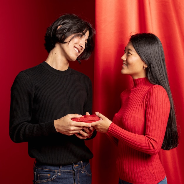 Pareja sonriente posando con regalo para año nuevo chino