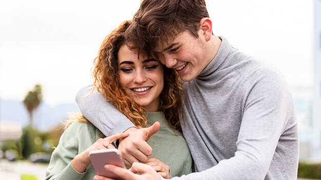 Pareja sonriente de primer plano con smartphone