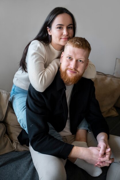 Pareja sonriente sentada en casa ángulo alto