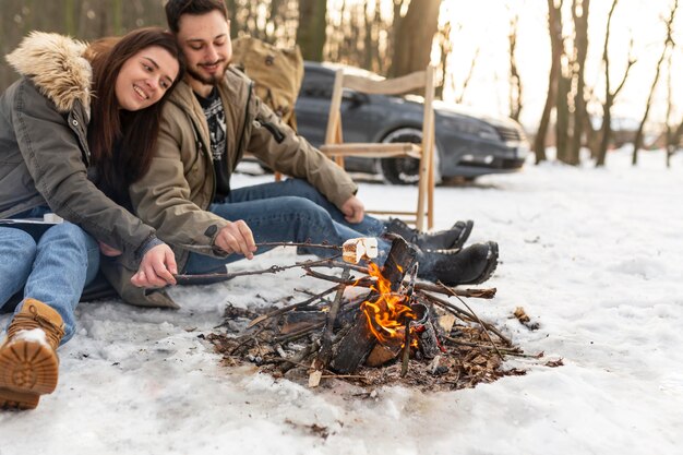 Pareja sonriente sentada cerca del fuego