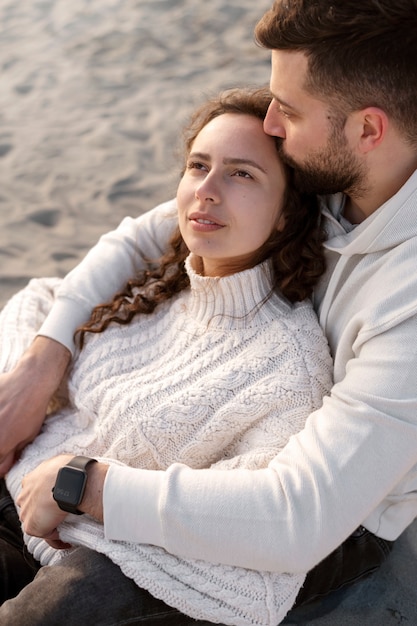 Pareja sonriente sentada en la playa de alto ángulo