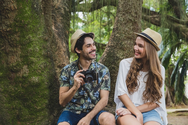 Pareja sonriente sentado en raíz de árbol