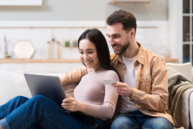 Pareja sonriente en el sofá haciendo algunas compras en línea