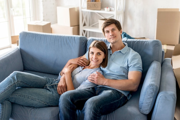 Foto gratuita pareja sonriente en el sofá mientras empaca para mudarse