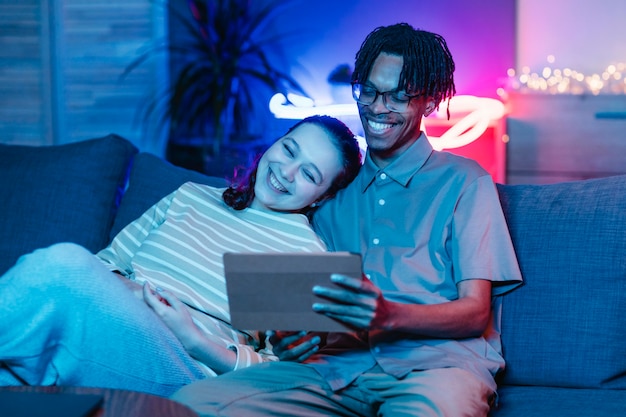 Pareja sonriente en el sofá con tableta