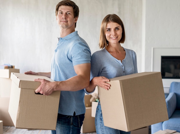 Pareja sonriente sosteniendo cajas en el día de la mudanza