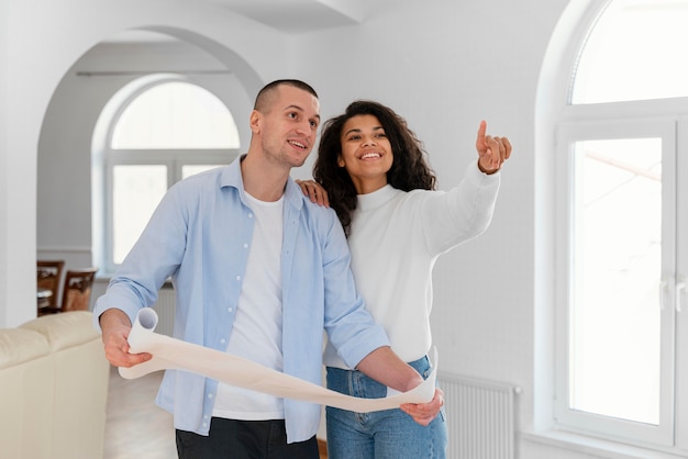 Pareja sonriente sosteniendo planes de casa