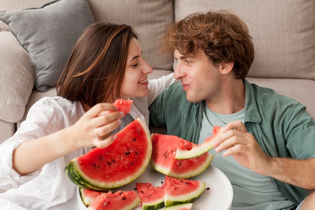 Pareja sonriente sosteniendo rodajas de sandía