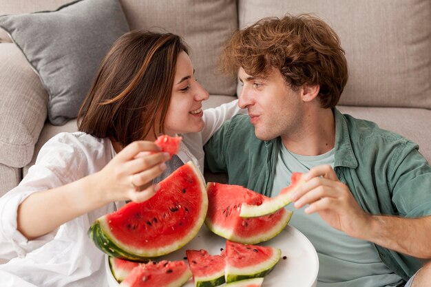 Pareja sonriente sosteniendo rodajas de sandía