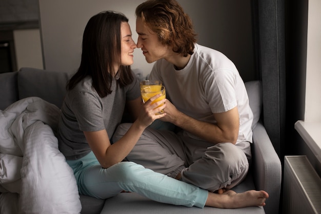 Pareja sonriente sosteniendo un vaso de jugo de naranja