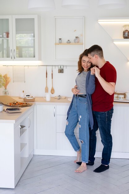 Pareja sonriente de tiro completo en la cocina