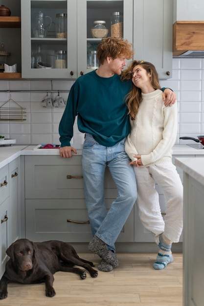 Pareja sonriente de tiro completo en la cocina