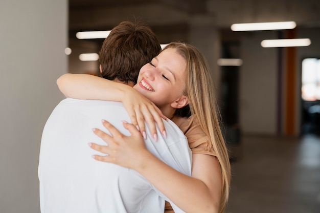 Pareja sonriente de tiro medio abrazándose