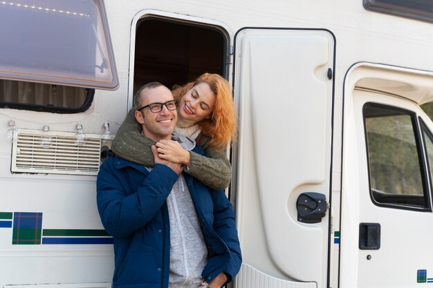 Pareja sonriente de tiro medio con autocaravana