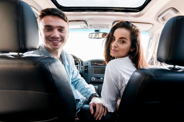 Pareja sonriente de tiro medio en coche