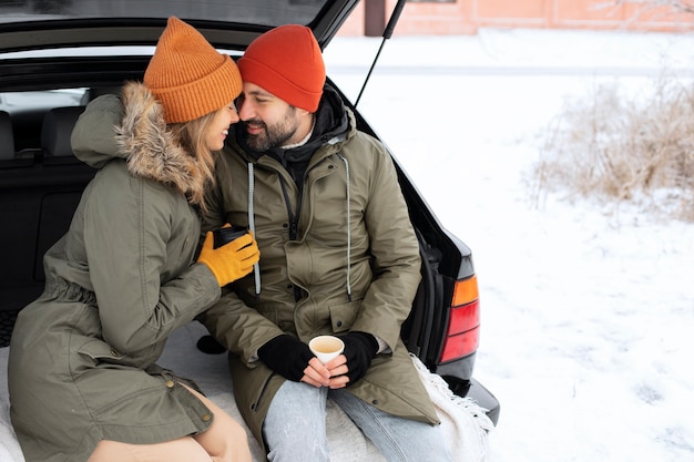 Pareja sonriente de tiro medio con coche