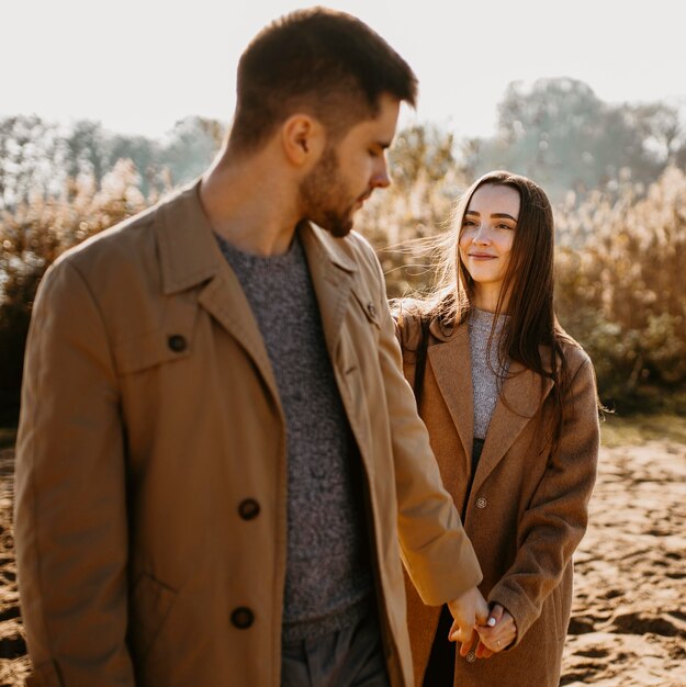 Pareja sonriente de tiro medio cogidos de la mano