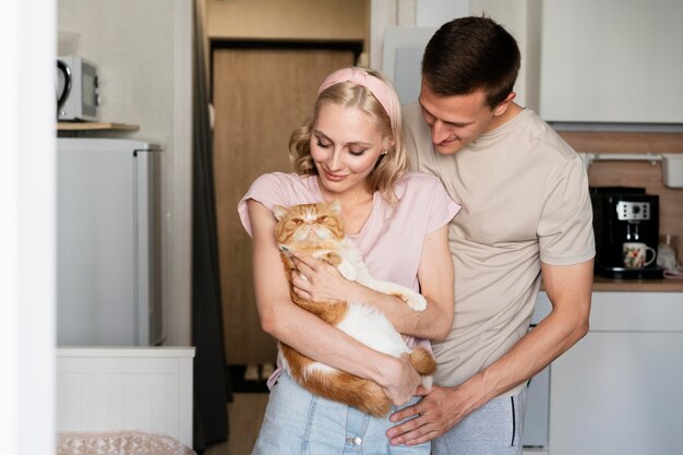 Pareja sonriente de tiro medio con gato