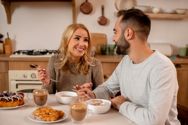 Pareja sonriente de tiro medio en la mesa