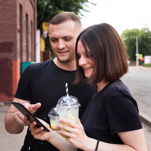 Pareja sonriente de tiro medio mirando el teléfono