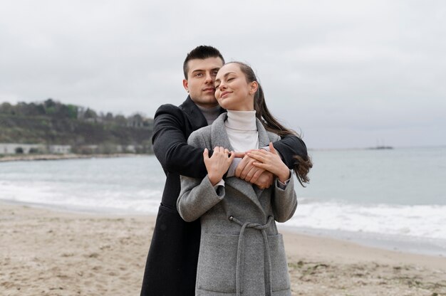 Pareja sonriente de tiro medio en la playa