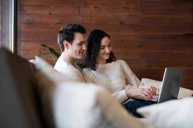 Pareja sonriente de tiro medio con portátil