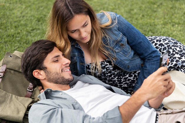 Pareja sonriente de tiro medio tendido sobre el césped