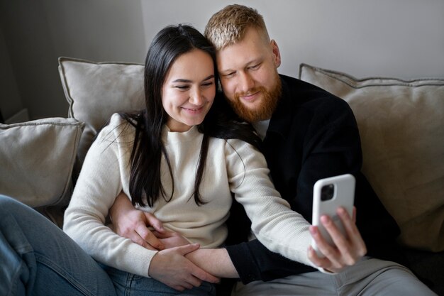 Pareja sonriente de tiro medio tomando selfie