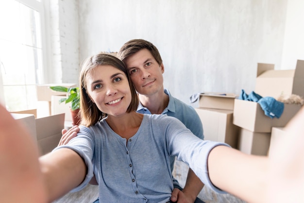 Foto gratuita pareja sonriente tomando un selfie mientras empaca para mudarse