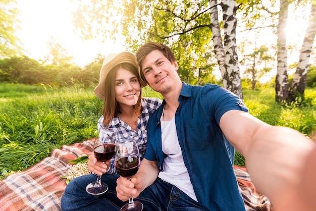 Pareja sonriente tomando selfie en picnic