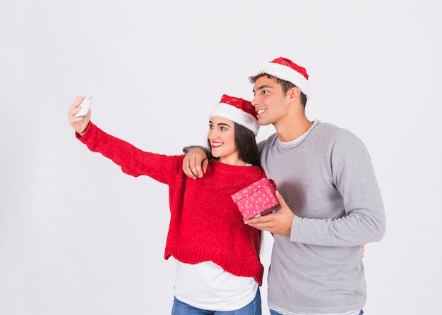 Pareja sonriente tomando selfie con regalo