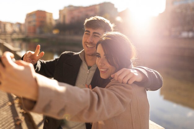 Pareja sonriente tomando selfie tiro medio