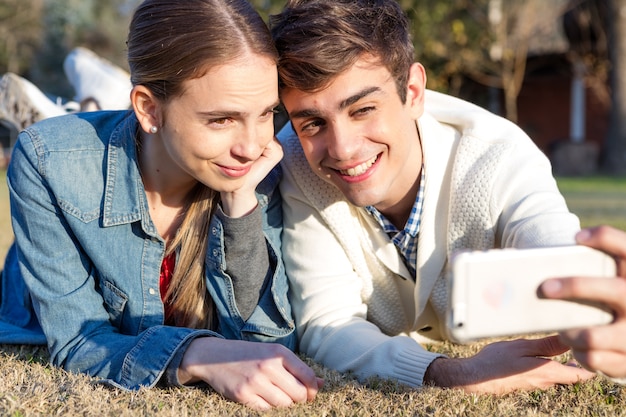 Pareja sonriente tomándose una foto en la hierba