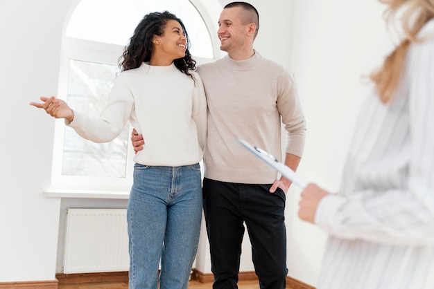 Pareja sonriente viendo nueva casa con agente inmobiliario femenino