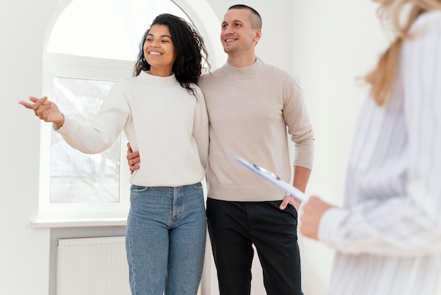 Foto gratuita pareja sonriente viendo nueva casa con agente inmobiliario