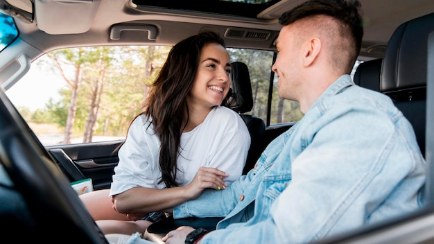 Pareja sonriente de vista lateral en coche