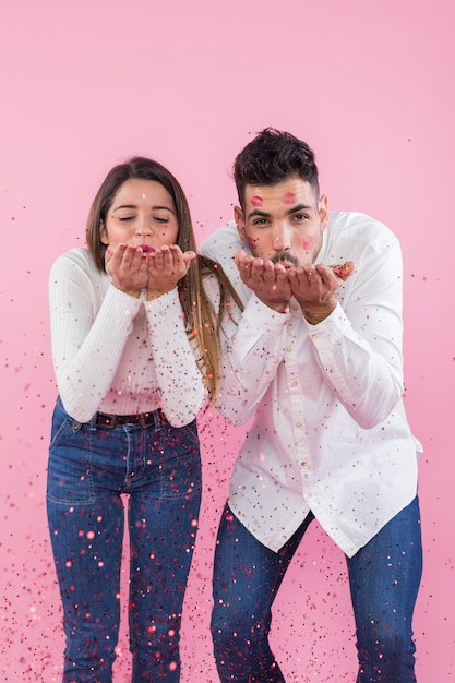 Foto gratuita pareja soplando confeti de manos