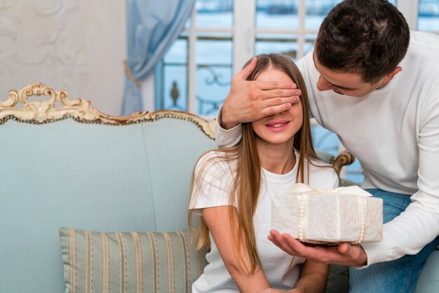 Pareja sorprendente con regalo en sofá