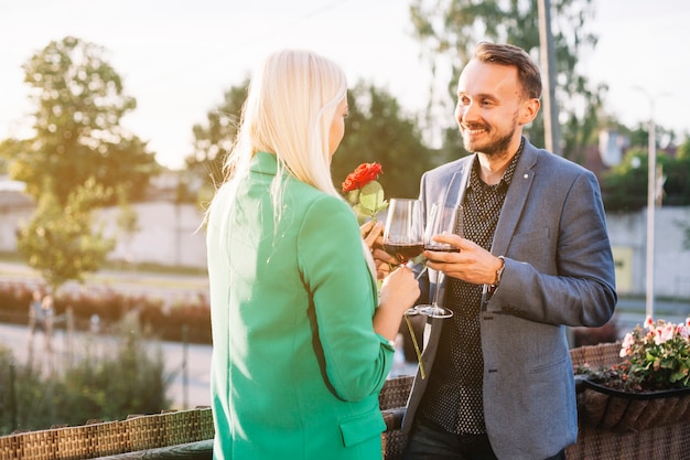 Pareja sosteniendo copas de vino besándose en el exterior