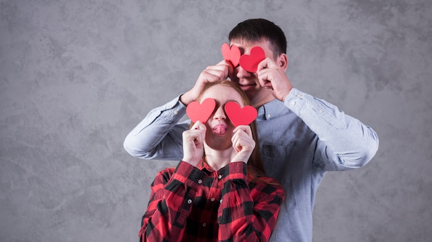 Foto gratuita pareja sosteniendo corazones de papel en los ojos