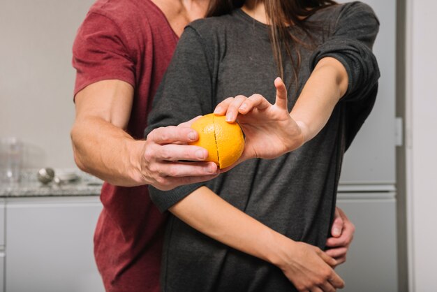 Pareja sosteniendo mitades de naranja en las manos