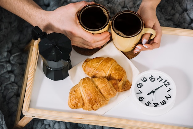 Pareja sosteniendo tazas de café en bandeja