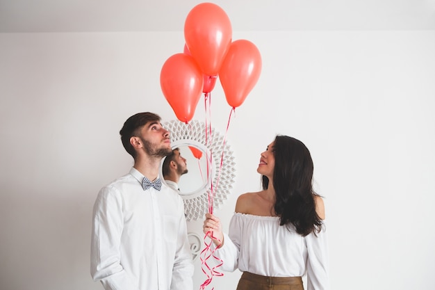 Pareja sujetando globos con forma de corazón