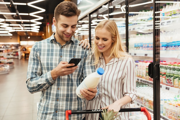 Pareja en supermercado leyendo la lista de compras