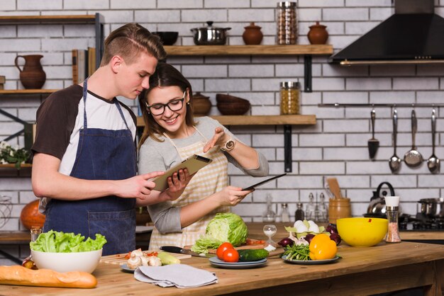 Pareja surfeando tableta y cocinando juntos